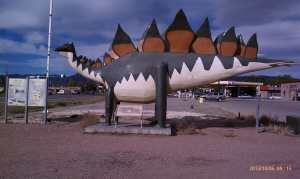 A dinosaur roaming just off the road.