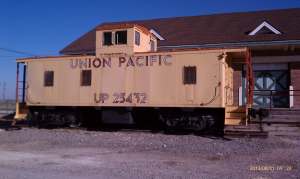 An old yellow caboose at the train depot.