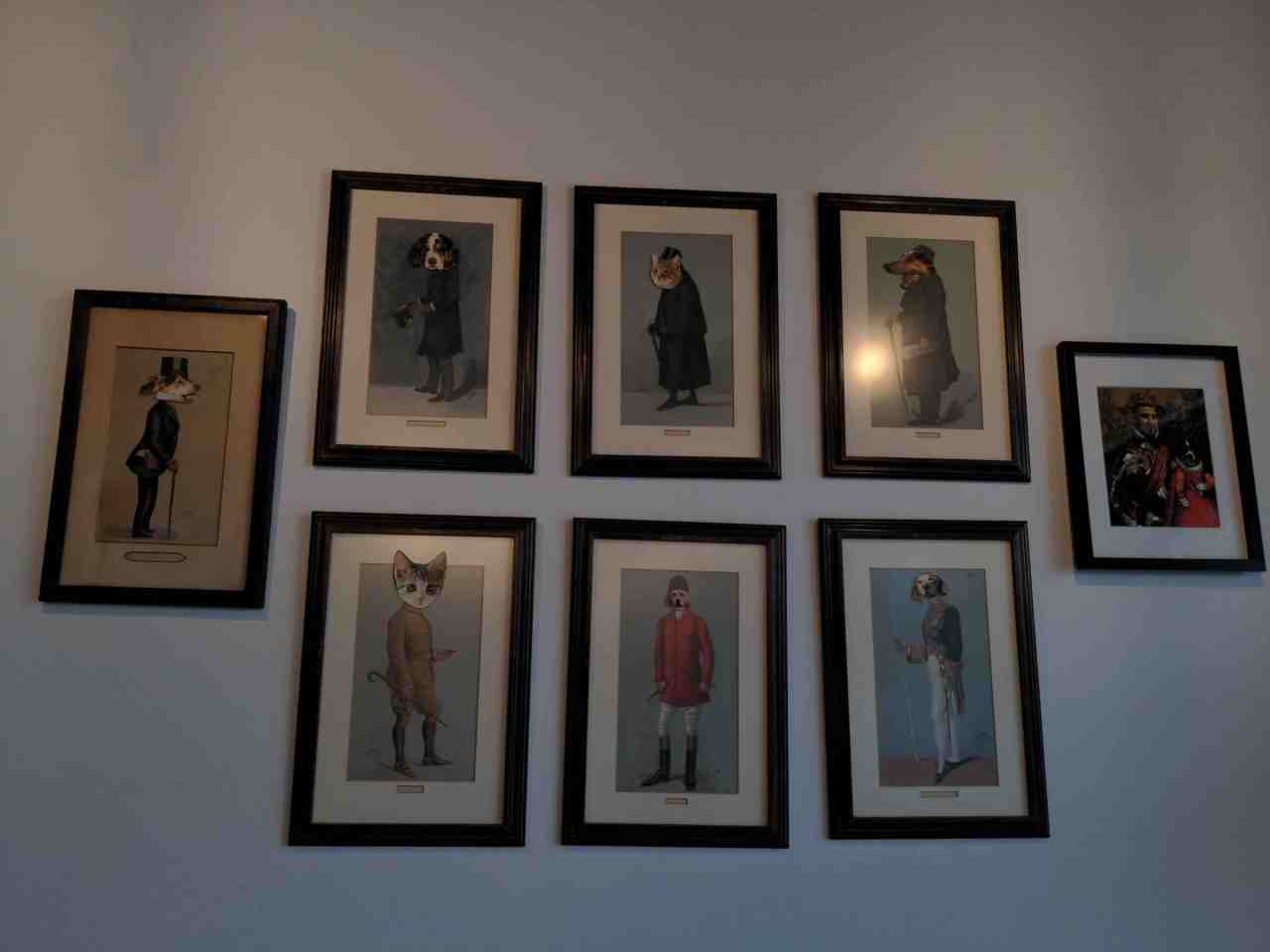 Pictures on wall of English looking minor royalty with cat and dog heads.