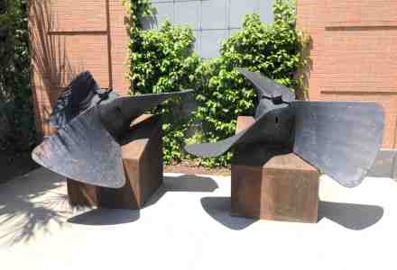 Two large metal propellers sitting on concrete blocks.