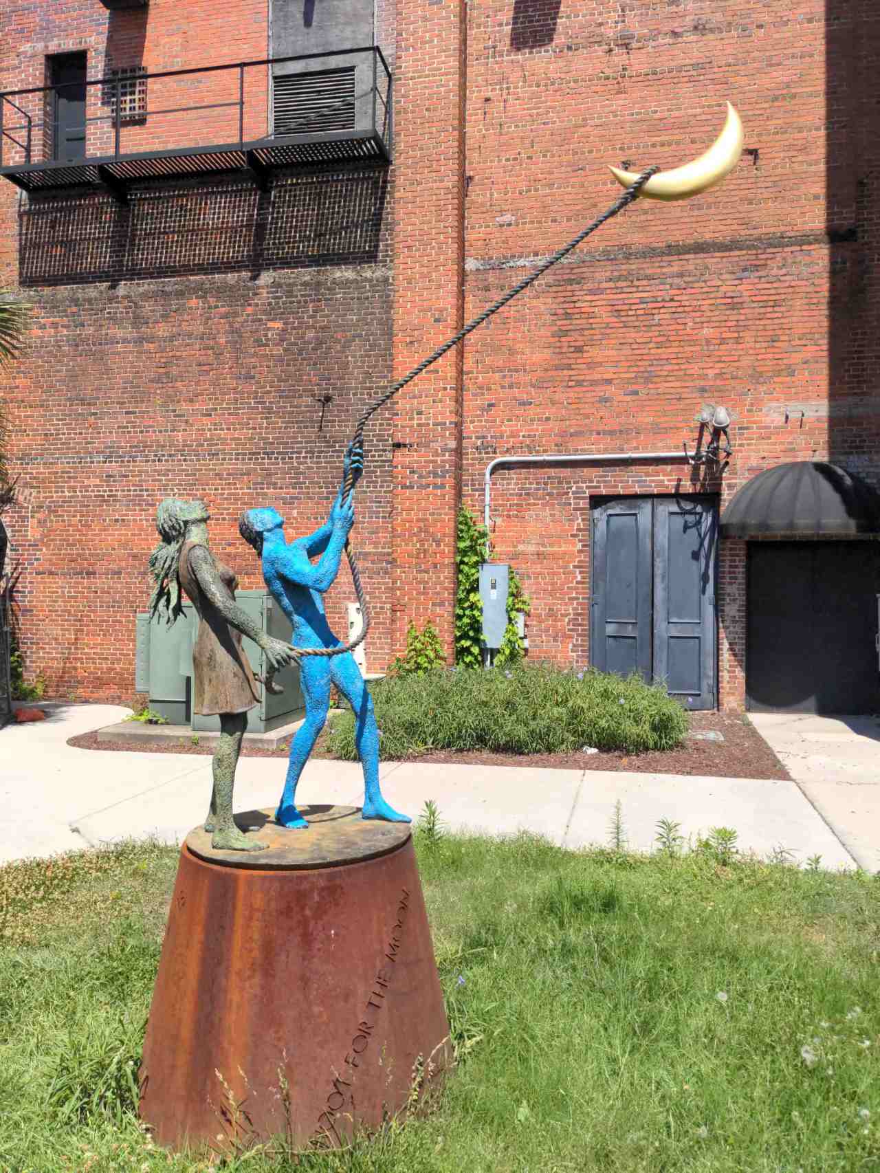 Sculpture of two kids with a lasso around the moon.