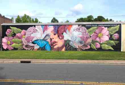 Long wall mural of vibrant colorful flowers and a face between them.