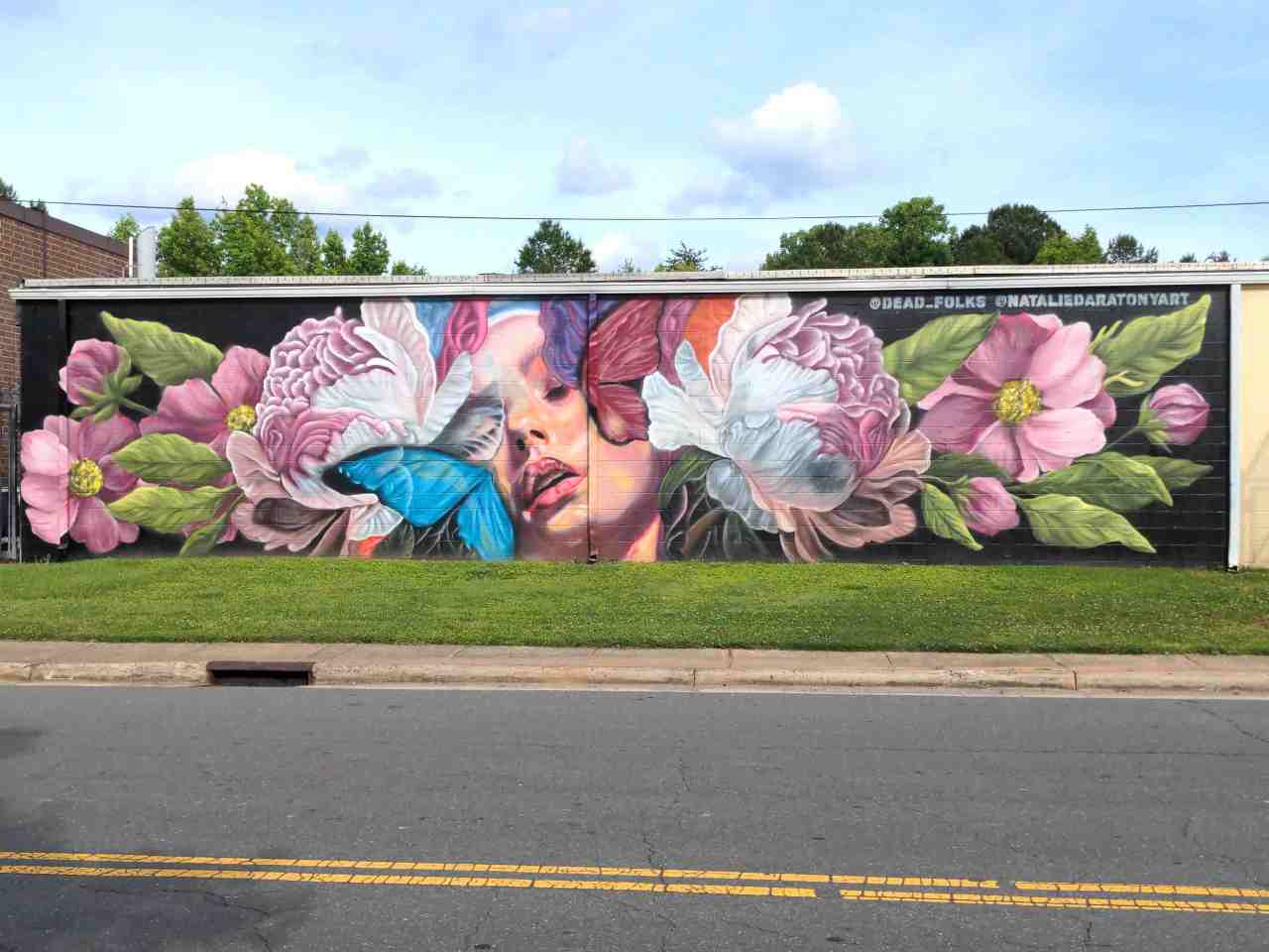 Long wall mural of vibrant colorful flowers and a face between them.