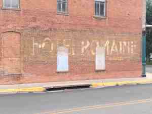 Side of brick building with fading letters of the Hotel Romaine.
