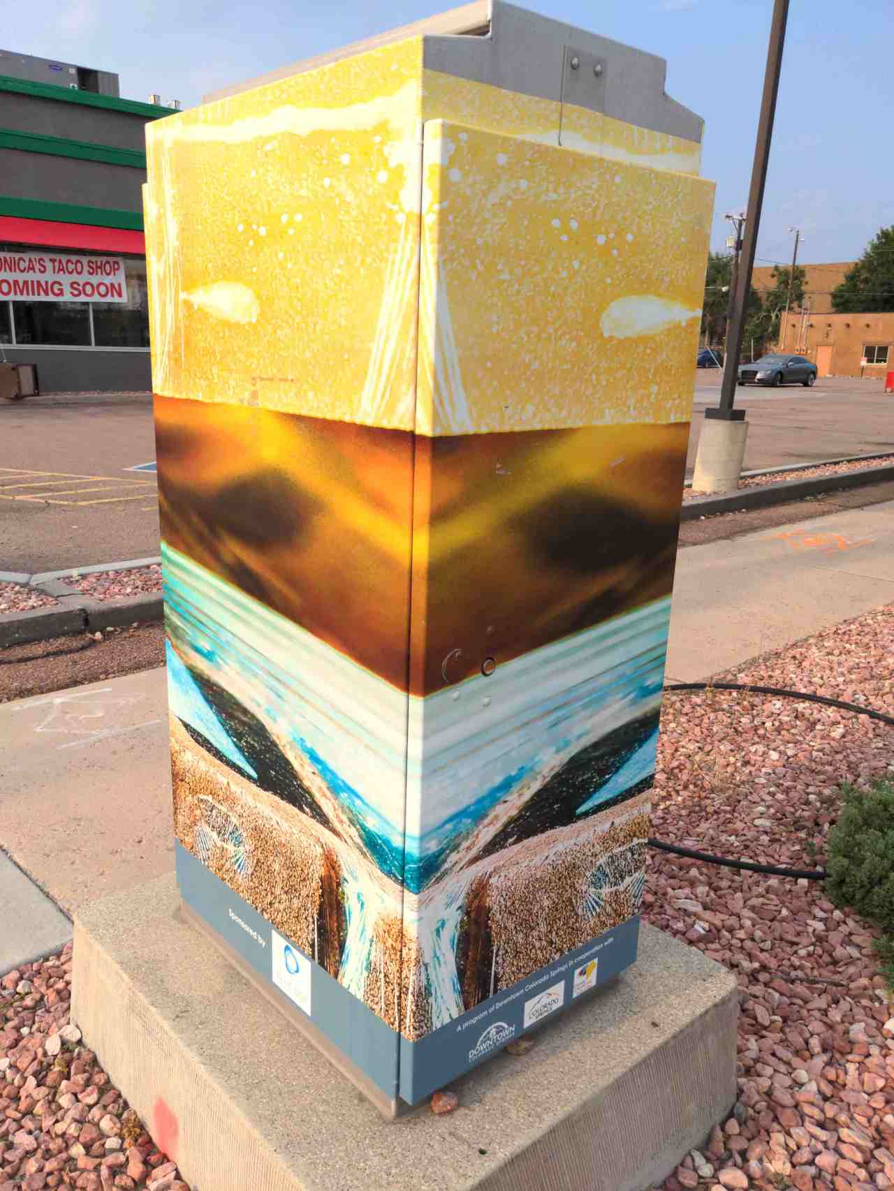 Miniture murals adorn a utility box on the street.