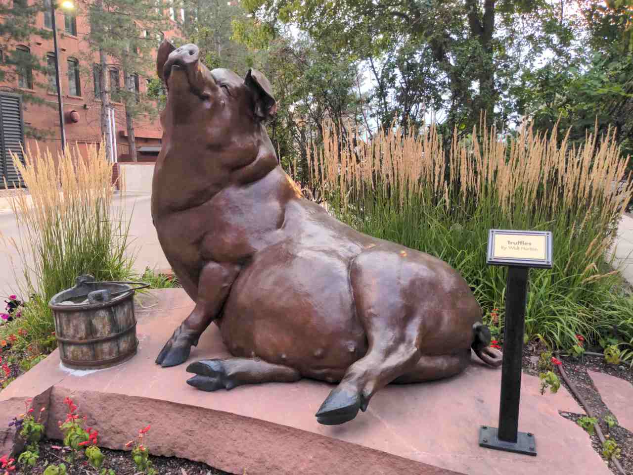 Bronze sculpture of a large pig lying on its side.