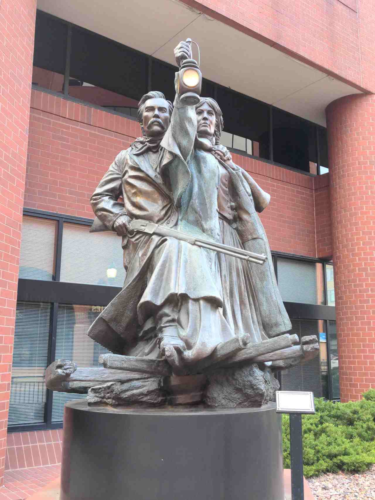Sculpture of man with rifle and woman with lantern.