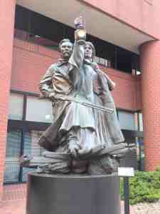 Sculpture of man with rifle and woman with lantern.