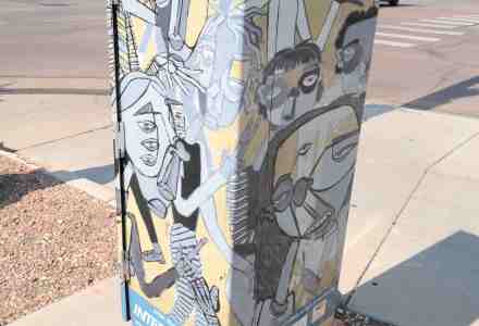 Mini mural of abstract people on utility box on street corner.