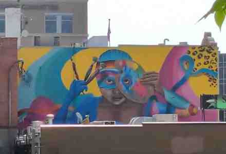 Colorful mural of artist with paint brushes and paint palette.