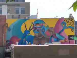 Colorful mural of artist with paint brushes and paint palette.