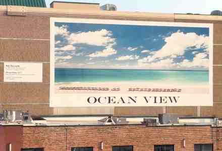 Large mural on building depicts a beautiful ocean view.