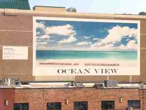 Large mural on building depicts a beautiful ocean view.
