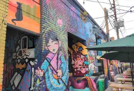 A wall painted mural full of cartoonish and anime type characters.